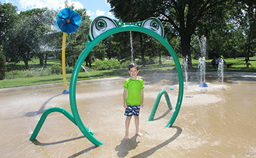 A boy using the splash pad at Noelridge Park